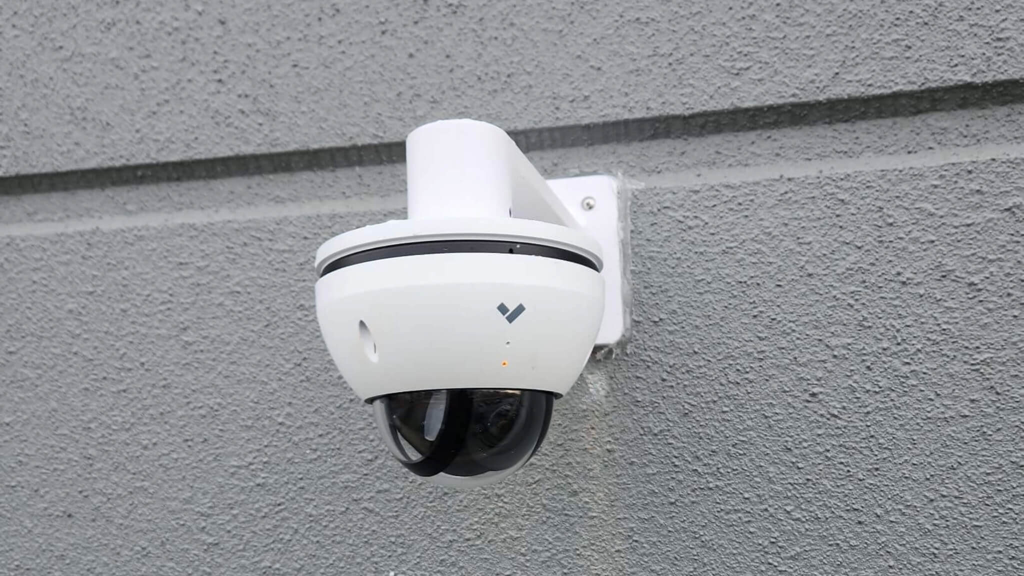 white verkada security camera hung on grey wall outside