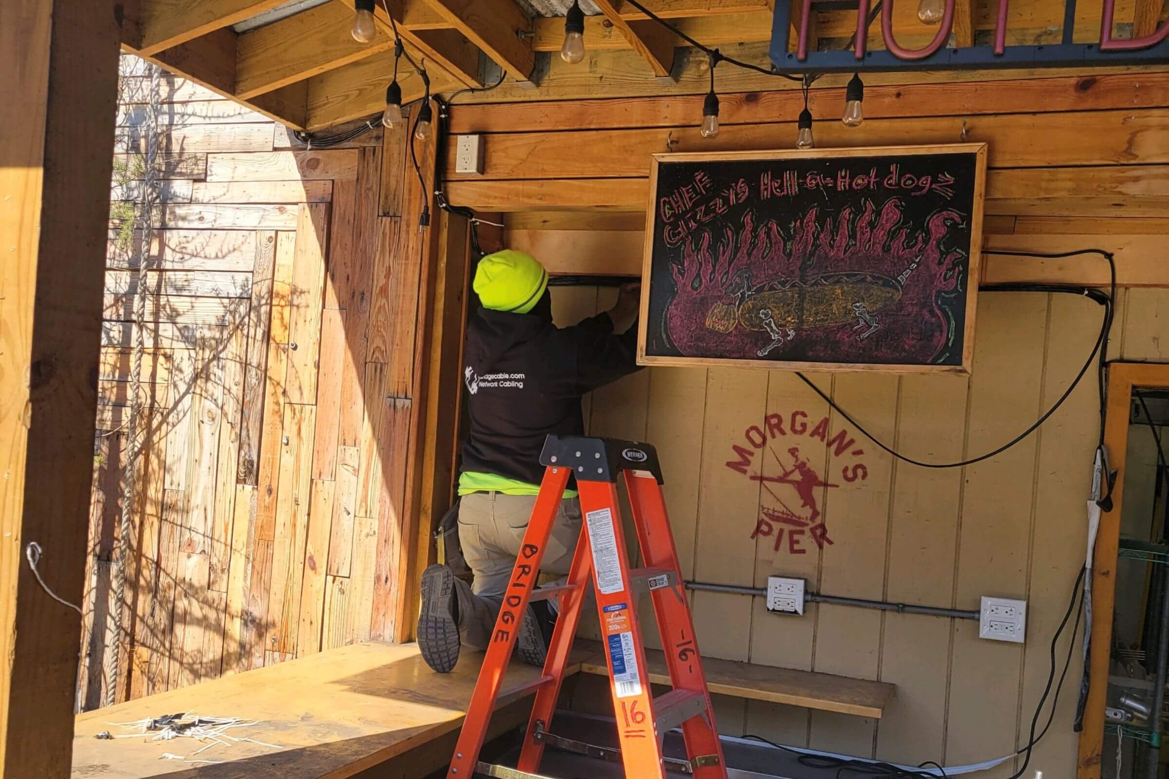 A technician installing cables at an outdoor restaurant