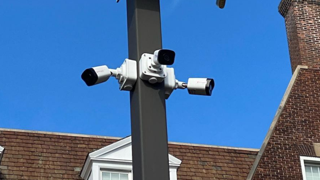 Three way security camera install with a blue sky and brick house background