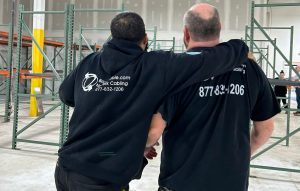 two network cabling technicians standing with their backs to the camera in black shirts aat a job site 