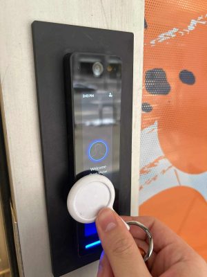 Person using RFID key fob on a modern access control system for secure contactless entry and smart building security management.