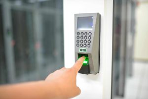 How Different Biometric Devices Improve Modern Access Control Systems 1 Person using a fingerprint biometric door access control system for secure commercial entry.