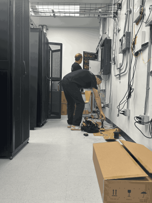 How Distribution Centers Depend on Reliable Structured Cabling Services for Peak Performance 3 Professional network technicians configuring structured cabling and IT hardware infrastructure inside a modern enterprise server room.