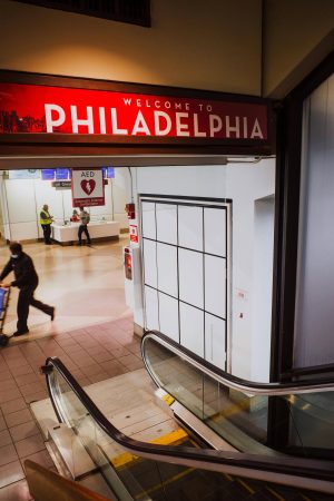 RF Interference Challenges During Network Cabling Installs Near Major Airports Like Philadelphia International 4 Welcome to Philadelphia sign above escalator inside airport terminal with travelers and airport interior visible.