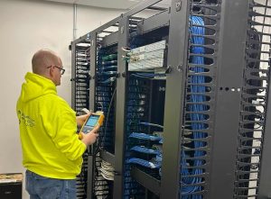 How Division 26, 27 & 28 Electrical Codes Support Structured Cabling and Security Infrastructure 3 Bridge Cable technician working on structured cabling installation and network rack infrastructure inside a commercial communications room.