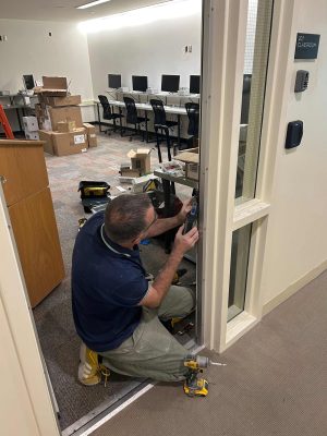 How Different Biometric Devices Improve Modern Access Control Systems 3 Technician installing a commercial door access control system in an educational facility.