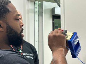 How Division 26, 27 & 28 Electrical Codes Support Structured Cabling and Security Infrastructure 4 Bridge Cable technician performing access control system installation on a commercial door security device inside a modern facility.