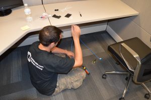 How Structured Cabling Supports Podcasters and Live Streamers 4 Bridge Cable technician installing Ethernet and data cabling underneath an office workstation during a structured cabling project.