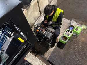 NAICS Code 238210 and Bridge Cable: Delivering Reliable Connectivity 3 Technician performing fiber optic fusion splicing using a fusion splicer and fiber tools during a commercial network installation.
