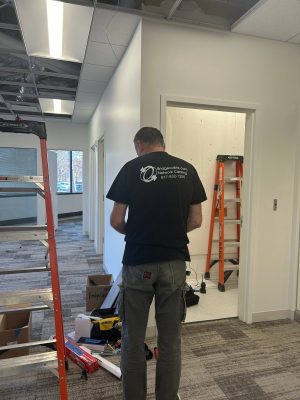Smart Crates for Animals and Bridge Cable 3 Network cabling technician working inside a commercial office space with ladders, tools, and open ceiling tiles during a structured cabling installation.