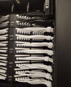 NAICS Code 238210 and Bridge Cable: Delivering Reliable Connectivity 2 Leviton Cat6 patch panels with organized black and white Ethernet patch cables installed in a network rack.