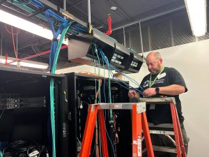 NAICS Code 238210 and Bridge Cable: Delivering Reliable Connectivity 1 Technician installing and managing structured cabling in data center racks with overhead cable pathways and network equipment.