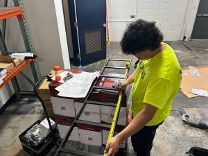 Getting Into Low Voltage Careers Through Trade Schools 4 Network cabling technician measuring a metal rack frame during a structured cabling installation project.