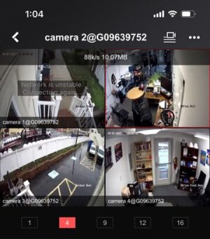 CCTV Contractor: CCTV vs AI Video Analytics in 2026 2 Mobile phone screen displaying a 4-camera split-screen CCTV app view with outdoor front and rear cameras, an office workspace camera, and an office front door camera.