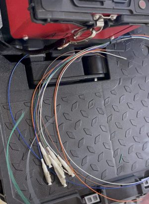 Fiber Optic Contractor Demand Soars This July 2 Multiple color-coded fiber optic cables with LC connectors laid out on a black rugged case, with a fusion splicer visible in the background.