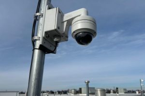 Allentown Structured Cabling Companies: Preparing Networks for Growth 3 White dome security camera mounted on a metal pole bracket against a blue sky, installed on a commercial building rooftop in Allentown structed cabling