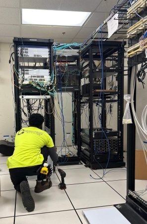 What Factors Affect a Structured Cabling Budget? 5 Technician working on cabling in server racks with patch panels and switches in an IT room.