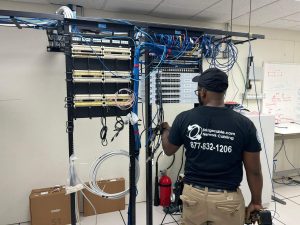 Wi-Fi 7 Business Connectivity in Pennsylvania 4 Technician wiring a network rack with patch panels and Ethernet cabling in an equipment room.