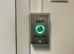 How Do You Choose the Right REX Devices? 1 Stainless steel touchless REX button labeled EXIT and SALIDA, mounted on a door frame with an illuminated green sensor ring.